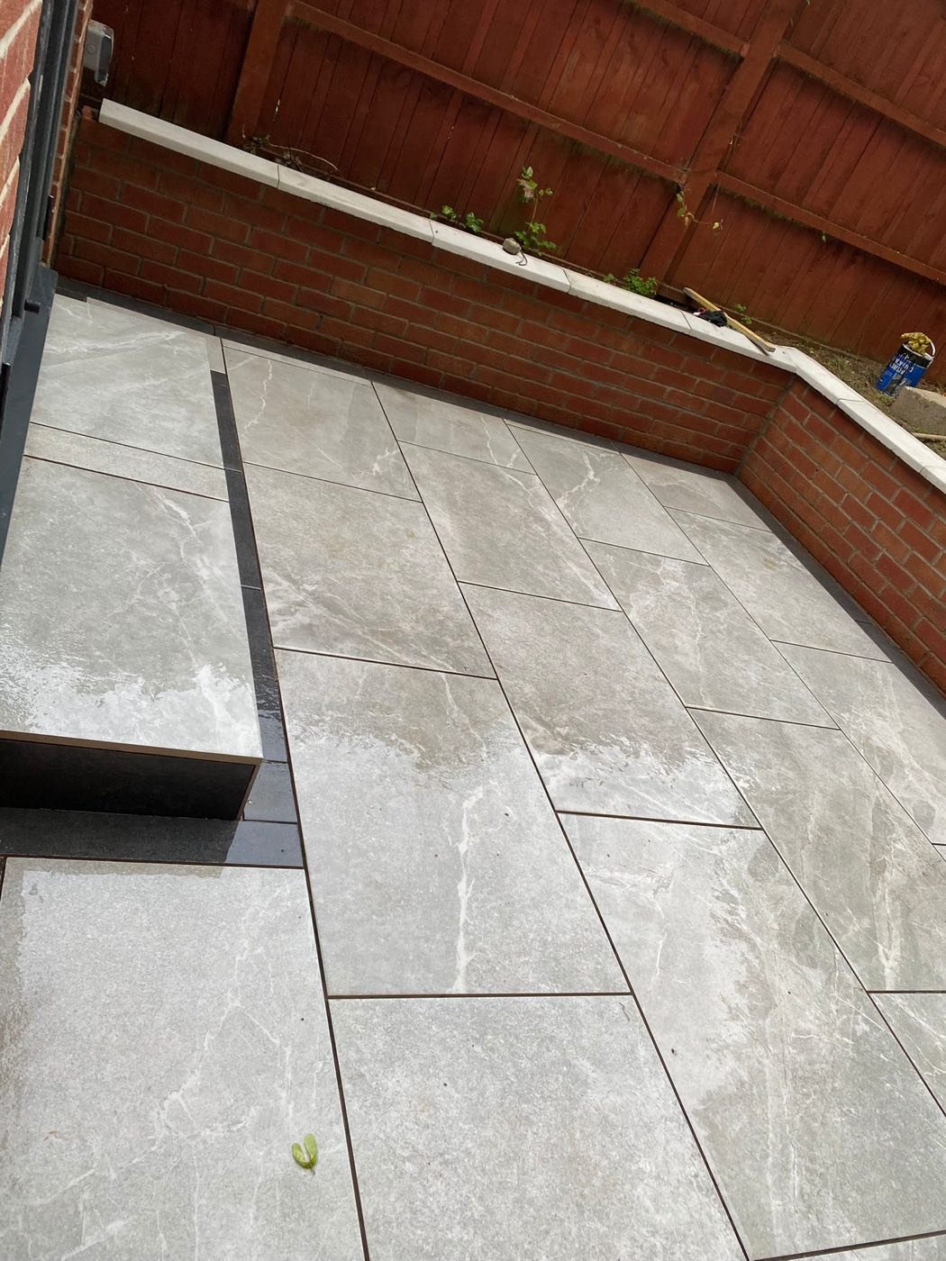 Grey marble-effect porcelain paving with charcoal step edge in a back garden by North West Landscapes