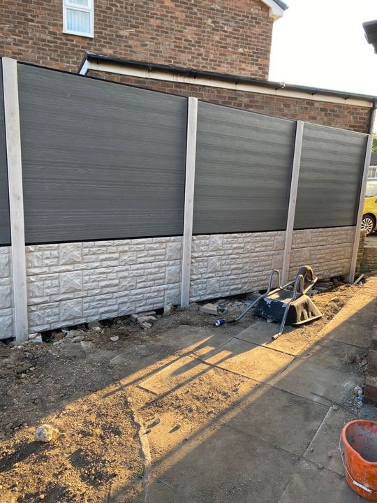 Grey composite fence panels with stone-effect concrete gravel boards installed by North West Landscapes, ground works still in progress