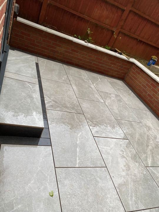 Grey marble-effect porcelain paving with charcoal step edge in a back garden by North West Landscapes