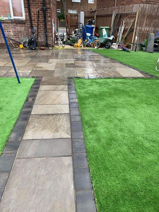 Indian sandstone patio with block-edged path and artificial grass by North West Landscapes in a back garden mid-project