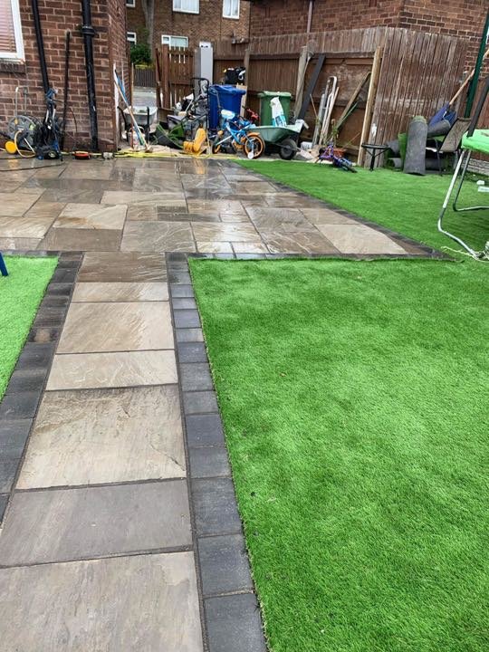 Riven Indian sandstone path with block paving edging and artificial lawn by North West Landscapes in a rear garden