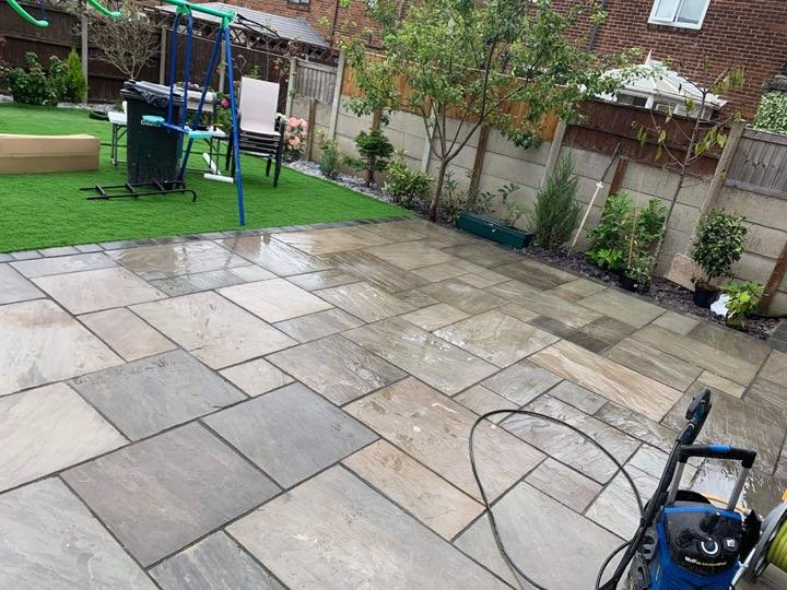Large Indian sandstone patio in a back garden by North West Landscapes, freshly laid and being cleaned