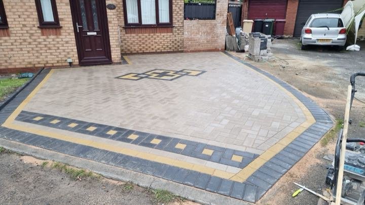 Buff block paving driveway with black and yellow border and Greek key feature by North West Landscapes