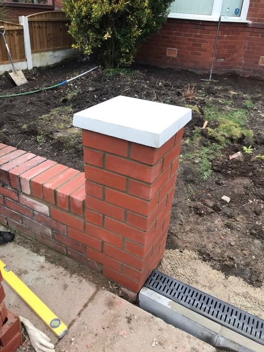 Red facing-brick garden wall and pillar with sandstone pier cap under construction by North West Landscapes