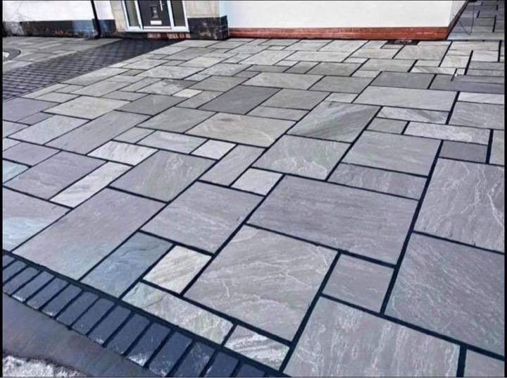 Grey riven Indian sandstone paving laid in a random pattern with dark pointing by North West Landscapes
