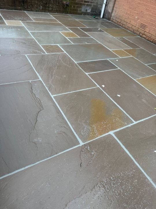 Grey riven Indian sandstone patio, freshly laid and pointed, by North West Landscapes