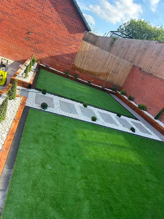 Artificial grass terraces with porcelain stepping stones and sleeper edging by North West Landscapes