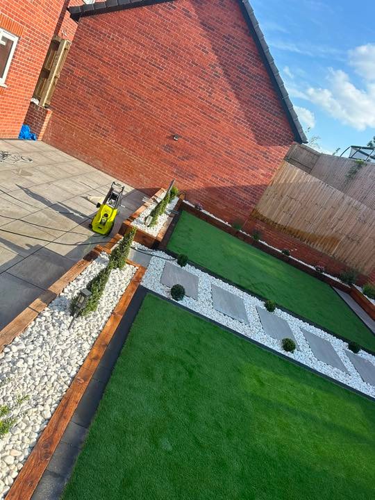 Garden with artificial turf, porcelain paving and timber sleepers by North West Landscapes