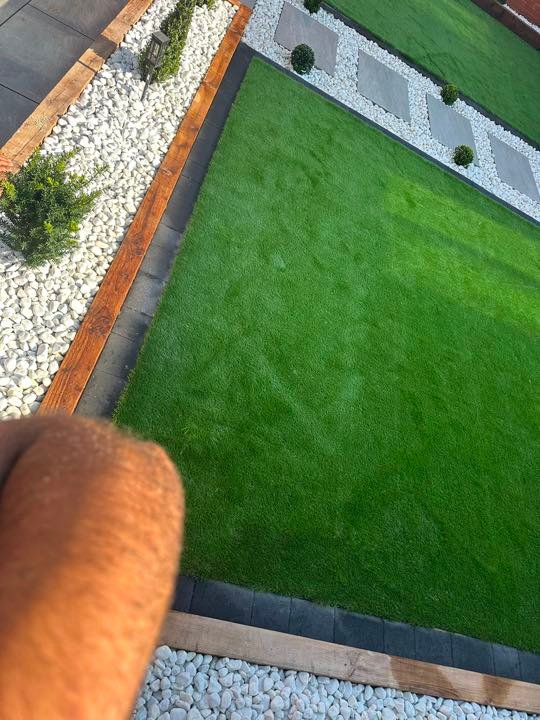 Artificial lawn with white cobble border and timber sleepers by North West Landscapes