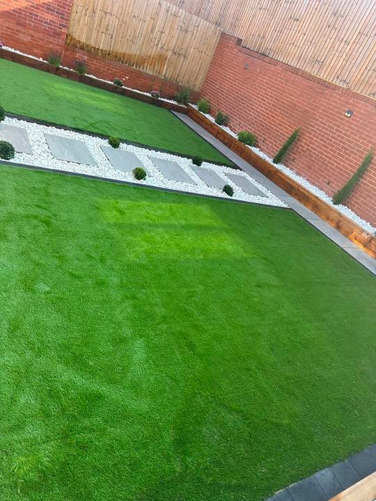 Artificial lawn and porcelain stepping stone path by North West Landscapes