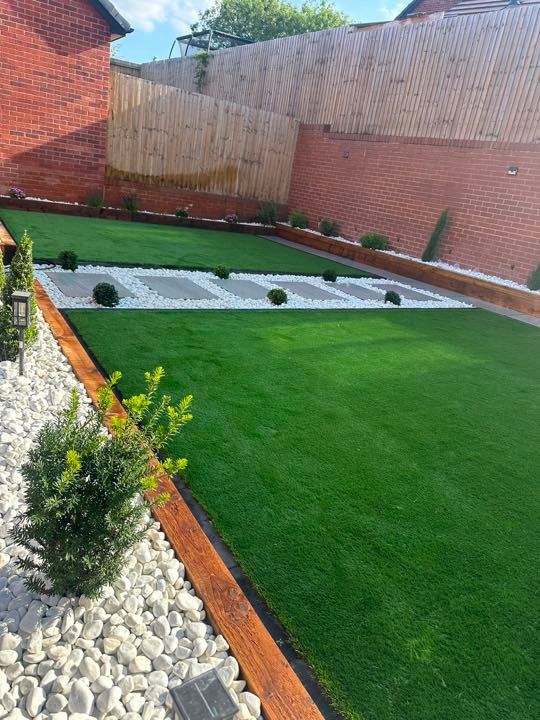 Two-tier artificial turf garden with sleeper borders by North West Landscapes